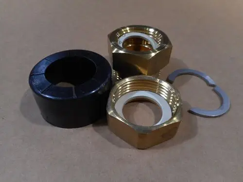 Drei Metallteile und ein schwarzes Gummiteil, möglicherweise für Heizungsinstallationen, markiert mit Remeha. Zwei Teile haben Gewinde, eines ist ein Sicherungsring.